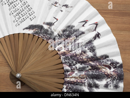 Traditional fan with natural motive on a wooden background. Stock Photo