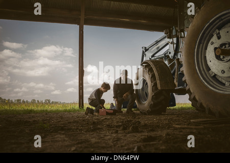 Caucasian father and son working on tractor Stock Photo