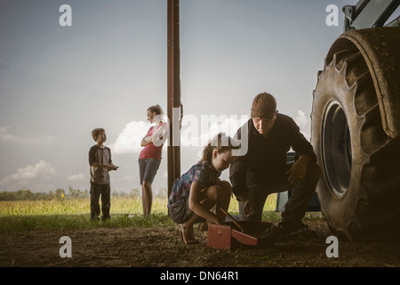 Caucasian father and daughter working on tractor Stock Photo