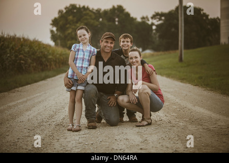 Caucasian farmer and family smiling on dirt road Stock Photo