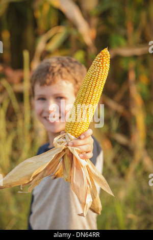 Caucasian boy holding ear of corn on farm Stock Photo