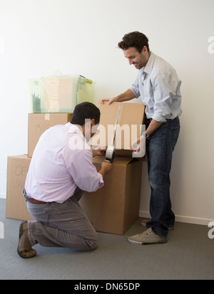 Hispanic men packing cardboard boxes Stock Photo