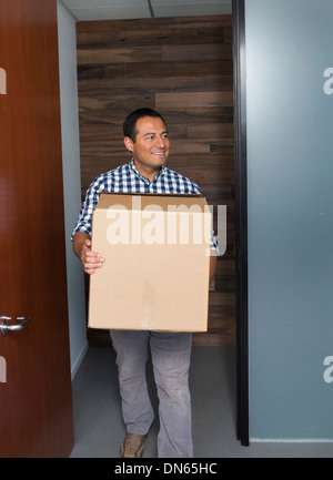 Hispanic businessman carrying cardboard box in office Stock Photo