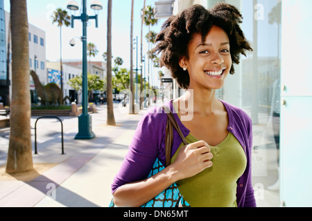 Mixed race woman smiling outside storefront Stock Photo