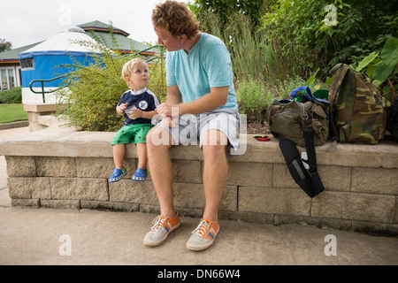 Caucasian father and toddler son sitting in park Stock Photo