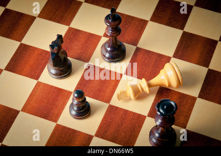 checkmate concept, with white king defeated and surrounded by black pieces Stock Photo