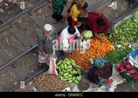 Dhaka, Bangladesh. 19th Dec, 2013. People buy and sell goods at the kitchen market on the rail lines in Karwan Bazar in the capital at 18 December 2013. Bazaar is the biggest and most famous wholesale general market in Dhaka City. All kinds of vegetables, fish, rice and other commodities are supplied to the small markets from here. Stock Photo
