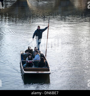 Cambridge, UK. 19th December 2013. Tourists enjoy punting in glorious winter sunshine on the River Cam, Cambridge UK 19th December 2013. There was a cloudless sky during the day with strong sun illuminating the famous 'Backs' of the University buildings and river. Credit Julian Eales/Alamy Live News Stock Photo