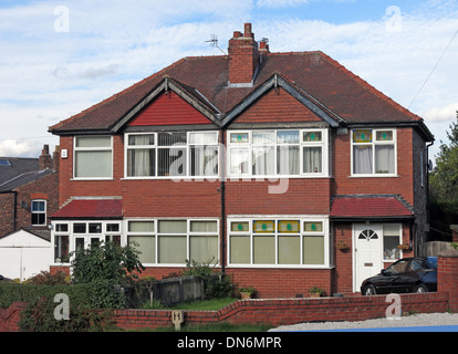 Typical 1930s English brick built semi-detached house with triangles over bedrooms, front garden shared chimney Warrington UK Stock Photo