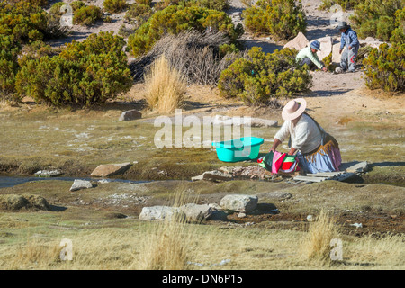 Indian woman washing clothes in the river, Mallcu Villa Mar village in high altitude desert, Bolivia, South America Stock Photo