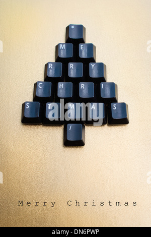 Christmas tree made of black computer keys with space for text, golden background Stock Photo