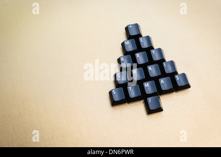 Christmas tree made of black computer keys with space for text, golden background Stock Photo