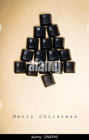 Christmas tree made of black computer keys with space for text, golden background Stock Photo