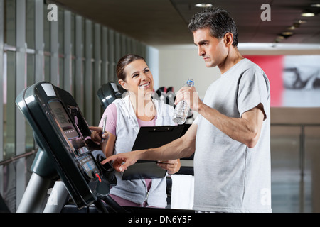 Instructor Looking At Male Client On Treadmill Stock Photo