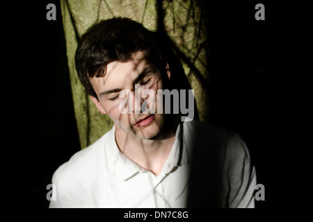 Young man with shadow of tree branches in the face Stock Photo