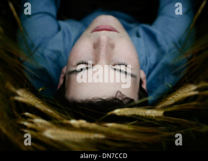 Young man lying in the field with closed eyes Stock Photo