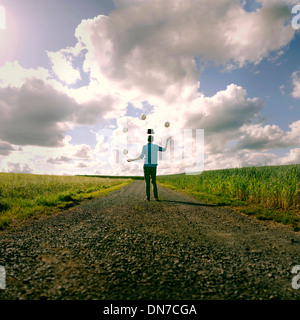 Young man with floating hat juggling in the field Stock Photo
