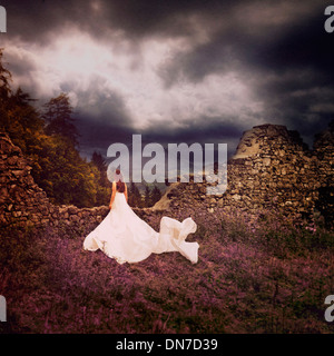 Woman in white dress standing on a ruined wall Stock Photo