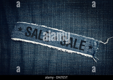 Sale title on Torn blue jeans texture. Commercial event in retail store. Stock Photo