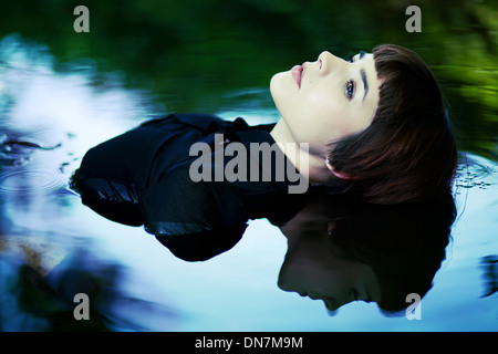 Young woman sitting in water, portrait Stock Photo