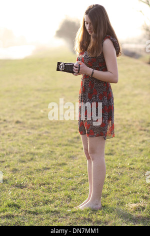 Young woman on a meadow with nostalgic camera Stock Photo