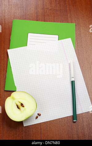 Blank sheet of school notebook, slice apple and felt-tip pens on table Stock Photo