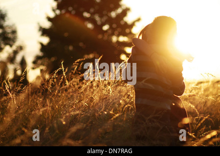 Young couple in love in the cornfield, kissing in backlight