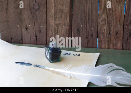 the feather and the ink-bottle on background of old boards Stock Photo