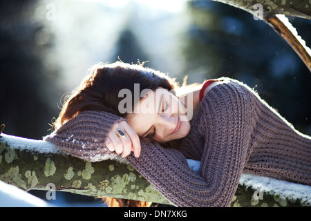 Young woman lying on a tree trunk in snow Stock Photo