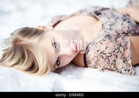 Young woman lying in snow, portrait