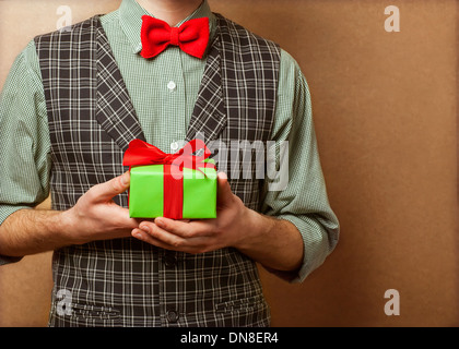 guy holding a gift in a suit and bow tie in a cage Stock Photo