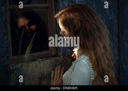 Young woman with reflection in window Stock Photo