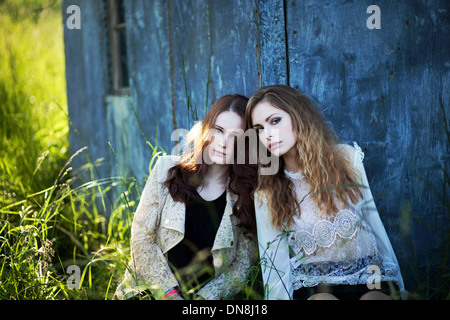 Two women leaning against a house wall Stock Photo