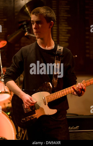 A fifteen year-old teenager sings and plays the guitar during a live gig in south London, UK. Stock Photo