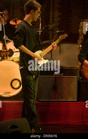 A fifteen year-old teenager sings and plays the guitar during a live gig in south London, UK. Stock Photo