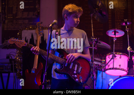 A fifteen year-old teenager sings and plays the guitar during a live gig in south London, UK. Stock Photo