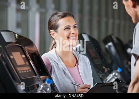 Instructor Looking At Male Client Exercising On Treadmill Stock Photo