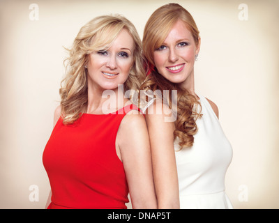 Portrait of two smiling sisters with blond hair standing together isolated on beige background Stock Photo
