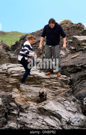 Young couple balancing on a rock.  Harlyn Bay, Cornwall, England Stock Photo