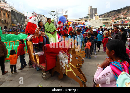 La Paz, Bolivia. 21st December 2013. An Aymara girl poses for an instant photo with Santa and his reindeer in Plaza San Francisco. Credit:  James Brunker / Alamy Live News Stock Photo