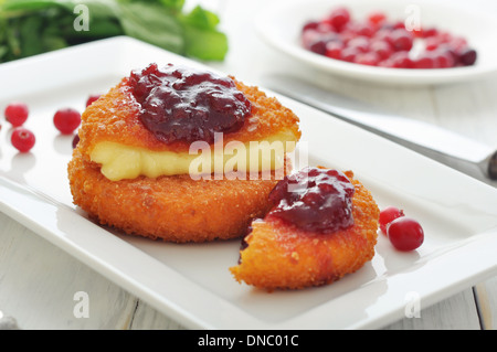 Breaded and baked camembert with cranberry sauce on white plate closeup Stock Photo