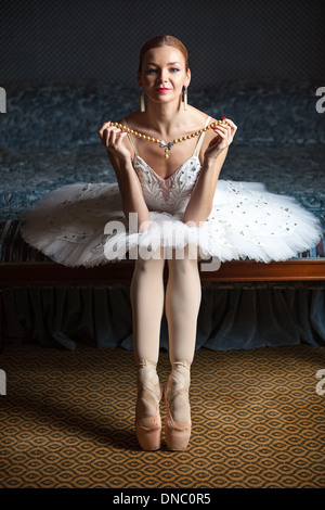 Ballerina holding pearl necklace and smiling in luxury interior Stock Photo