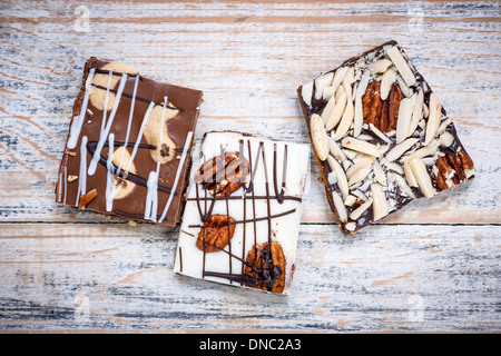 Three assorted chocolate caramel bark pieces as sweet dessert arranged on wooden background from above Stock Photo