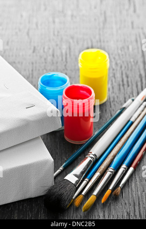 Various sizes of paintbrushes with blank canvas and paints