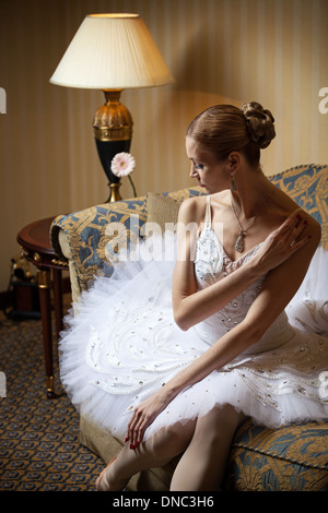 Professional ballet dancer sitting on sofa and looking down Stock Photo