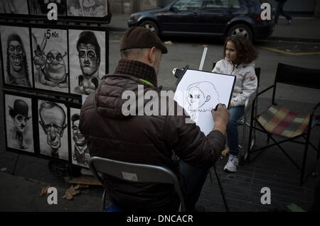 Barcelona, Spain.22nd Dec, 2013. A painter paints a caricature in the Rambla. The city center of Barcelona is filled with walkers and visitors during the first weekend of the Christmas holidays. Credit:   Jordi Boixareu/Alamy Live News Stock Photo
