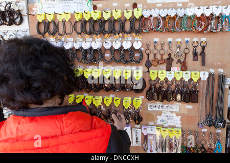 Woman shopping for Buddhist prayer beads (mala) at temple gift shop - Gyeongju, South Korea Stock Photo