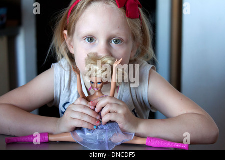 Girl age 6 playing with Barbie Doll doing the splits. Lodz Central Poland Stock Photo