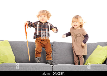 Brother and sister standing and playing on a sofa Stock Photo