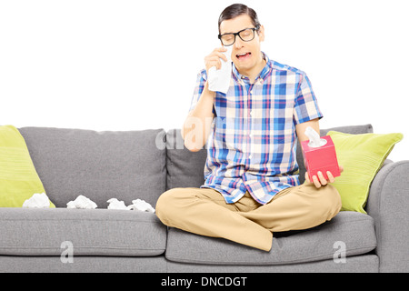 Sad guy sitting on a sofa and wiping his eyes from crying Stock Photo